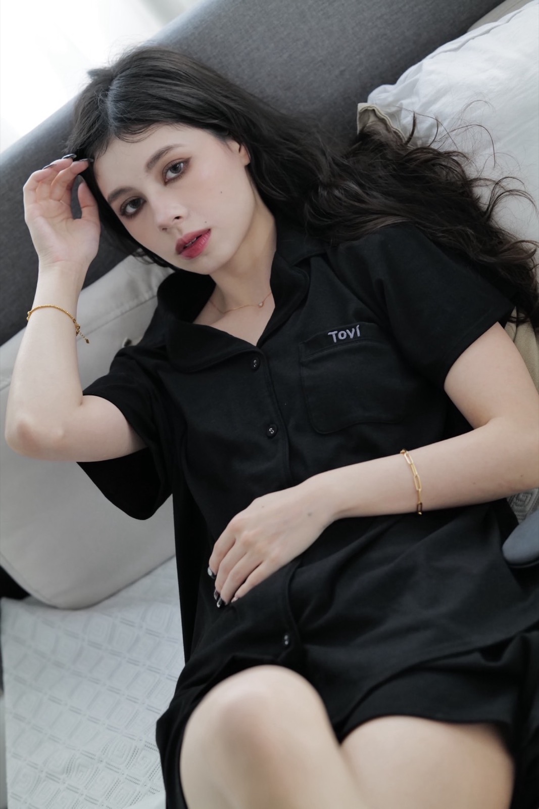 Model reclining in black Tovi sleepwear on a sofa