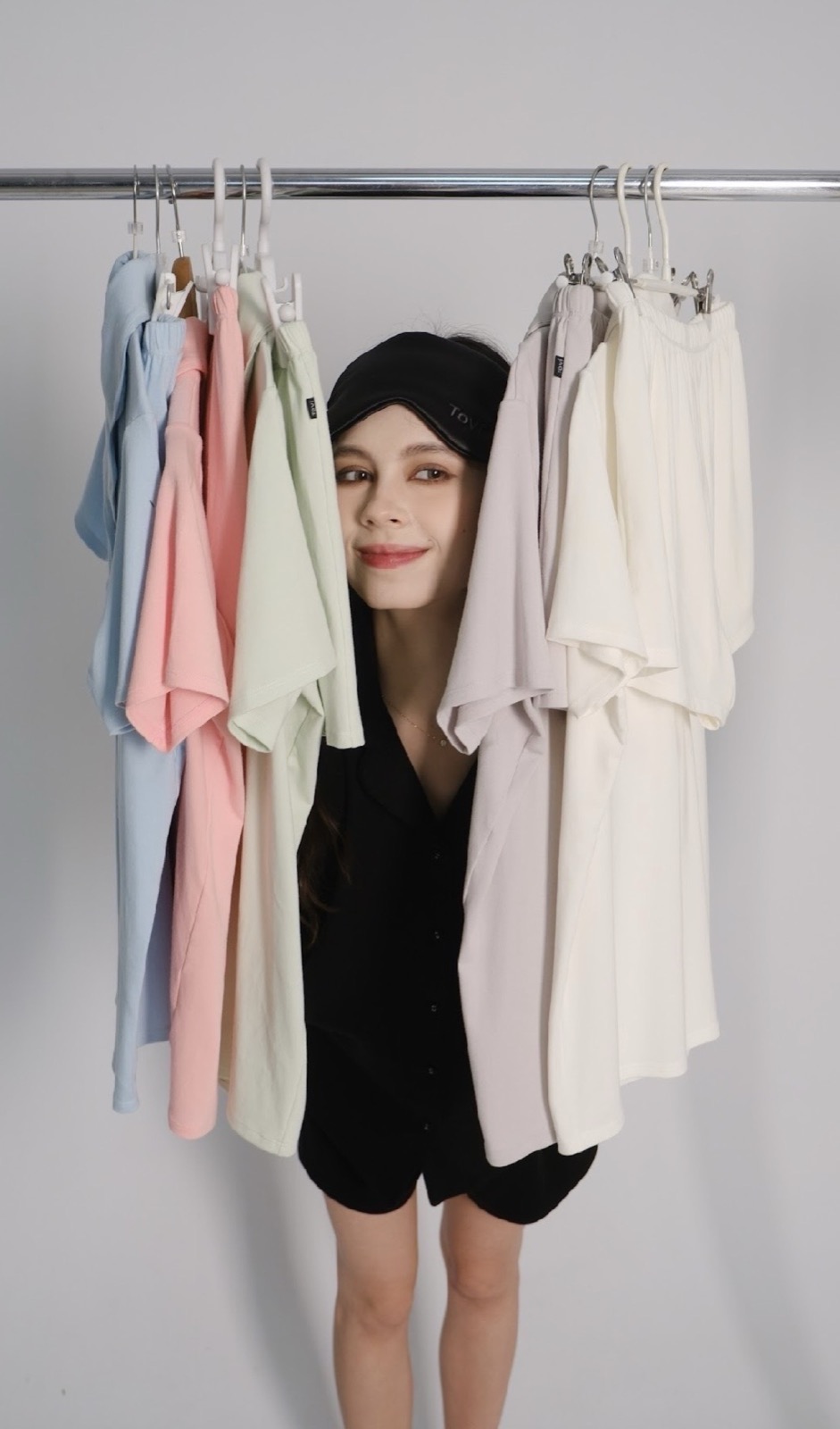 Model peeking through a rail of pastel Tovi sleepwear sets