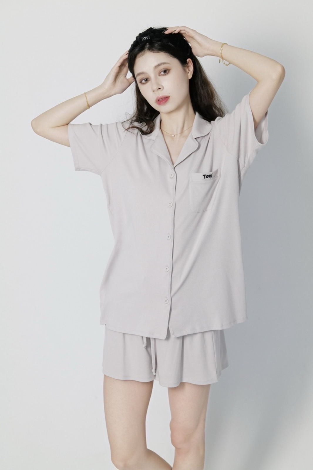 Model in stone gray Tovi sleepwear adjusting a braided sleep headband